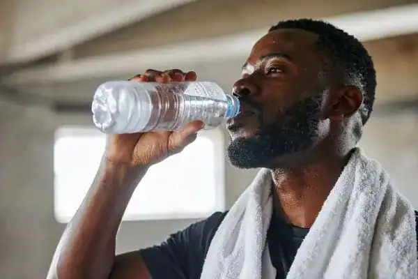 Image of man drinking water to improve hydration Market Harborough after work out.